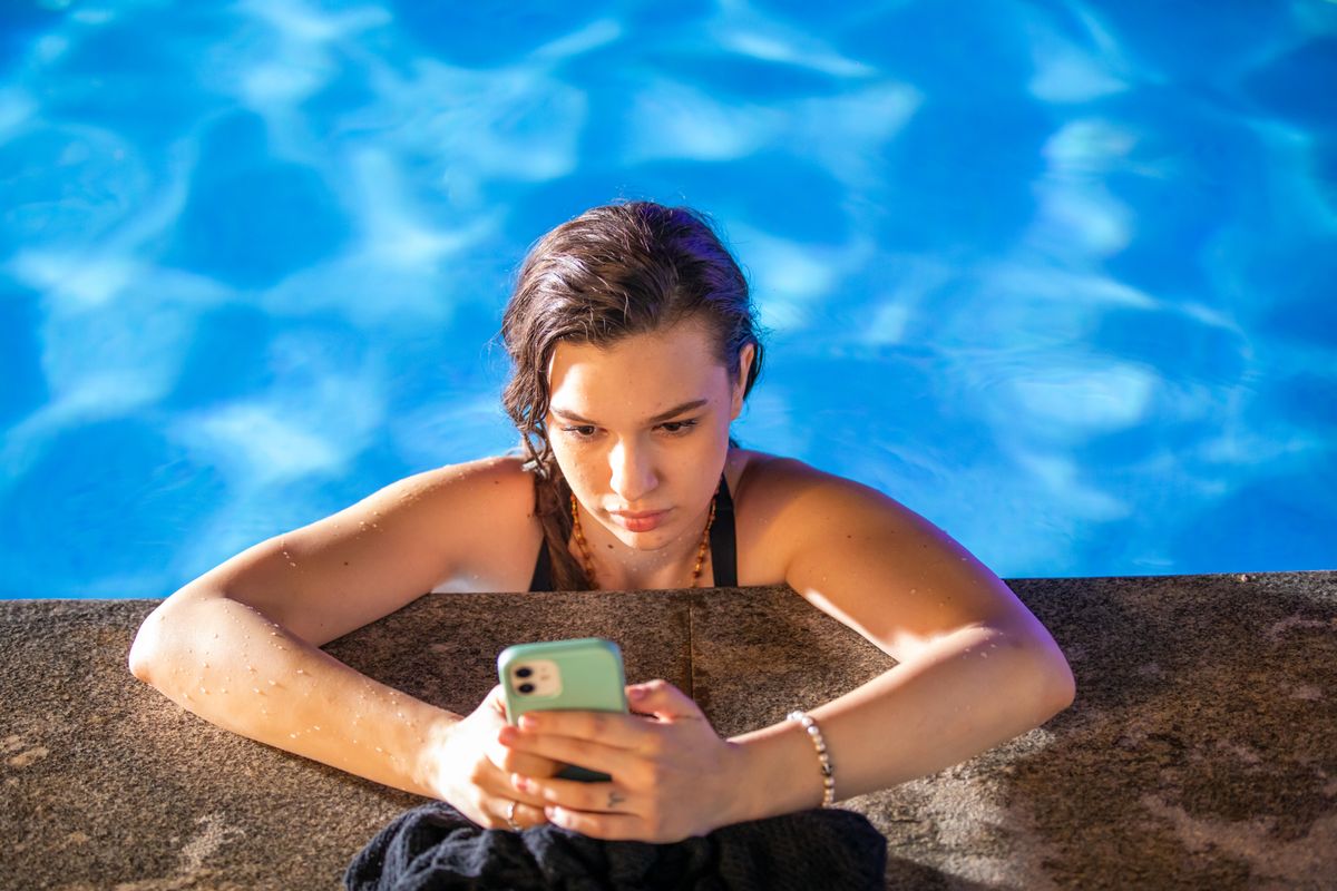 Young woman checking her phone, smiling at a message.